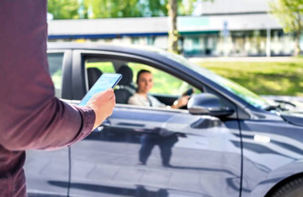 Taxi phone app for cab or car ride share service. Customer waiting driver to pick up on city street. Man holding smartphone.